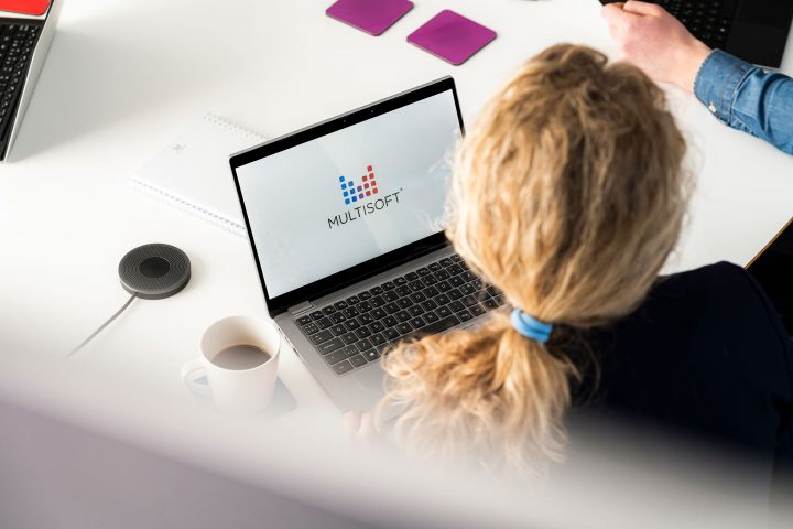 Blond kvinna, lockigt hår, framför digital system, dator, multisoft logga