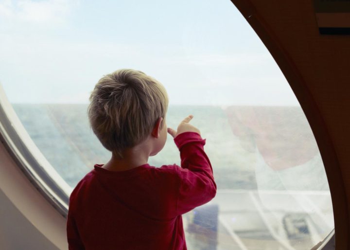 Boy admiring ocean from ship window