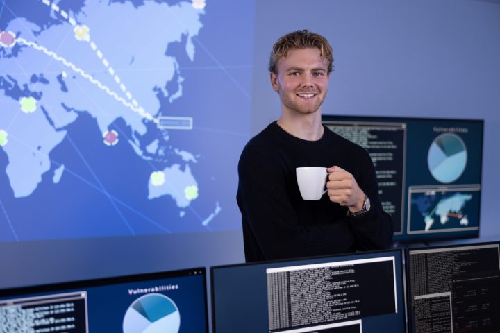 Ung man står med en kaffekopp framför en NOC
