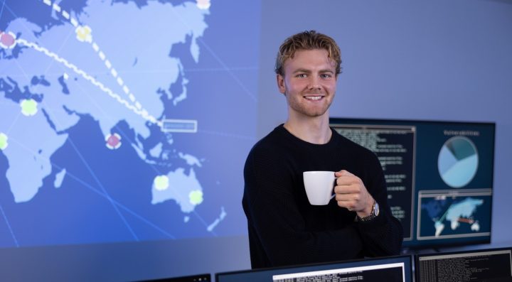 Ung man med kaffekopp står framför en NOC