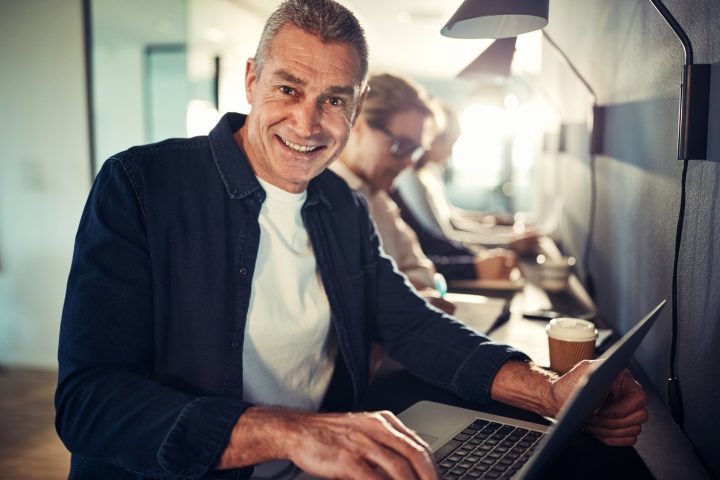 Man siter vid dator och ler