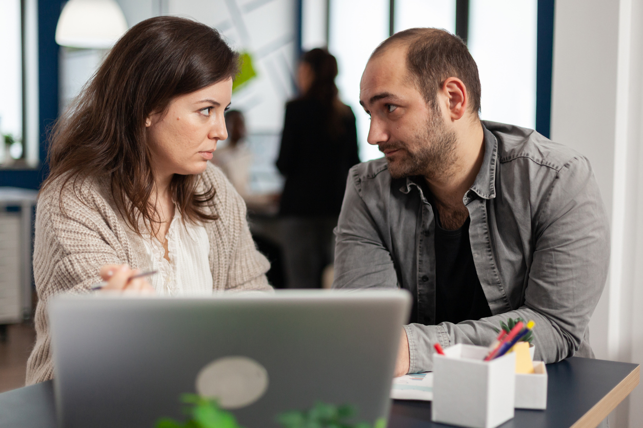 Två kollegor sitter vid en dator och tittar på varandra